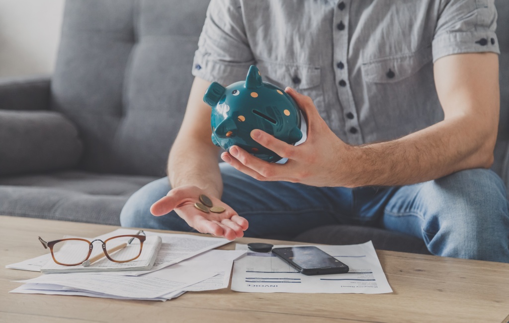 man-sitting-table-full-unpaid-bills-shakes-out-last-penny-from-piggy-bank-spend-your-last-savings-unemployment-poverty-bankruptcy-concept.jpg копилка